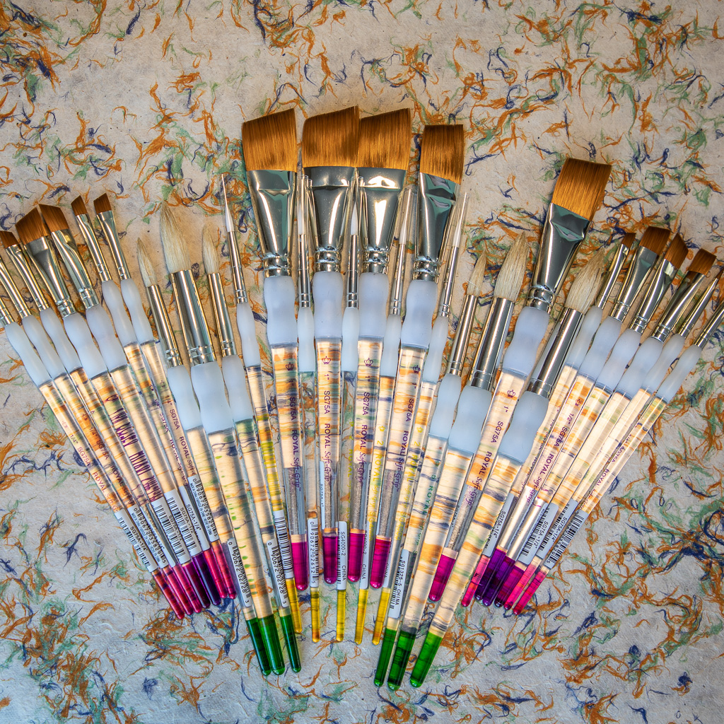 New paint brushes laid out on textured paper background
